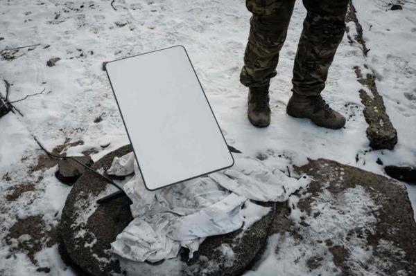 A Ukrainian serviceman stands next to the antenna of the Starl<em></em>ink satellite-ba<em></em>sed broadband system