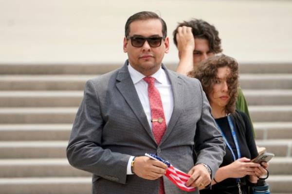 FILE - U.S. Rep. George Santos, R-N.Y., holds a miniature American flag that was presented to him as he departs federal court, June 30, 2023, in Central Islip, N.Y. Prosecutors say the ex-campaign treasurer for Santos is scheduled to enter a guilty plea to an unspecified felony in co<em></em>nnection with the federal investigation of financial irregularities surrounding the indicted New York Republican. Nancy Marks is a veteran Long Island political operative. Marks was a campaign treasurer and close aide to Santos during his two co<em></em>ngressional bids. (AP Photo/John Minchillo, File)