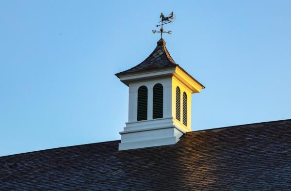 A cupola, used for ventilation, and a weathervane top the barn structure.