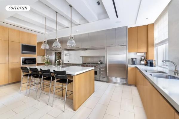 A spacious kitchen with dual refrigerators, a large island, and stainless steel appliances located in 9 East 79th Street co-op.