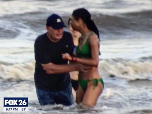 Woman in a bathing suit with a bloody hand in the water being looked at by a man offering aid.