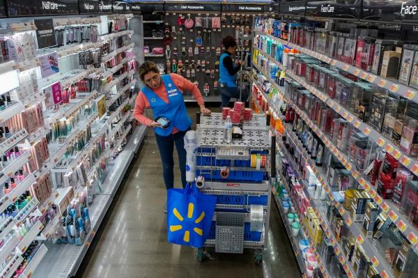 A Walmart store aisle with beauty products and a cart pushed by a woman.