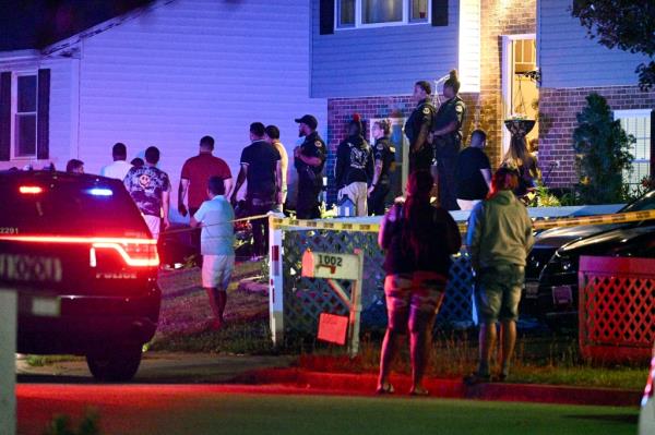 Police stand among a crowd outside a home wher<em></em>e multiple people were shot in Annapolis, Md., on June 11, 2023. 