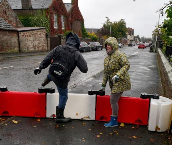 Residents of Edzell in Angus climb over flood defences in the village, ahead of anticipated dangerous levels of rain in the area (Picture: PA)