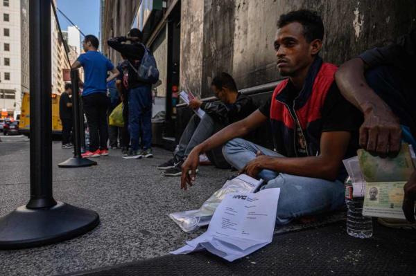 Recently arrived migrants from Mauritania wait with their docu<em></em>ments outside a processing center in New York on July 28, 2023. 