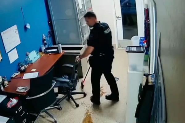 The cop is seen cleaning up the mess King made after placing the Husky back in his kennel. 