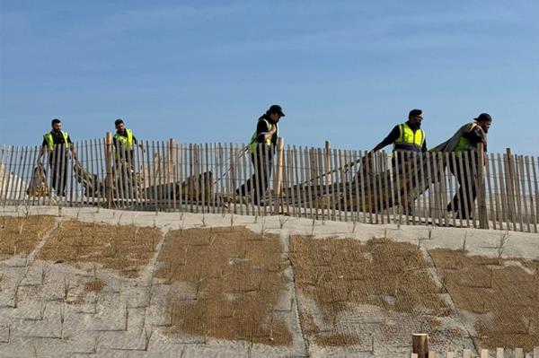 Five workers in yellow vests dragging the emergency slide.