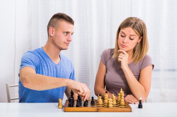 Young couple sitting at the table and playing chess.