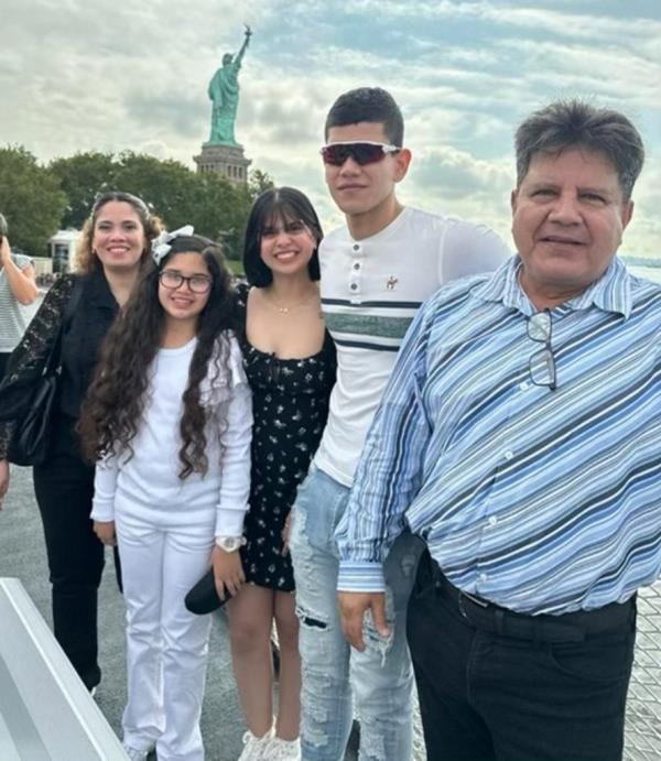 Mariangel Vargas with family smiling and posing in front of Statue of Liberty.