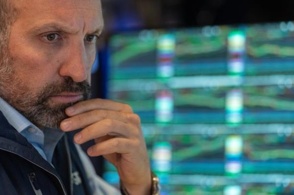 A worried trader working on the floor of the New York Stock Exchange as eco<em></em>nomic data reveals signs of a weakening economy, causing a significant drop in Dow, S&P 500, and Nasdaq