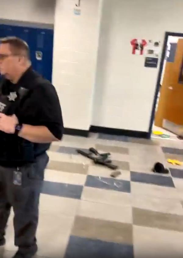 A law enforcement official stands in a hallway inside Apalachee High School near the suspected rifle used in Wednesday's shooting.