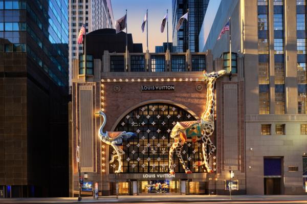 A building with a large entrance, decorated with giraffes and flags for Louis Vuitton's holiday issue E57th 2024