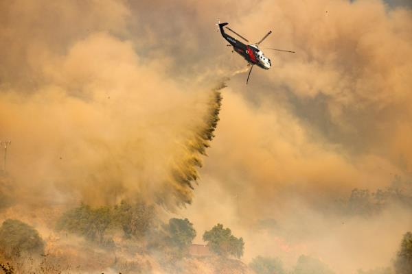 A firefighting helicopter makes dro<em></em>p over the Mountain Fire in Camarillo Heights, Camarillo, California, on November 6, 2024. 