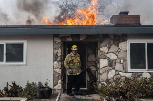 A LAFD Firefighter walks out of a burning house. 