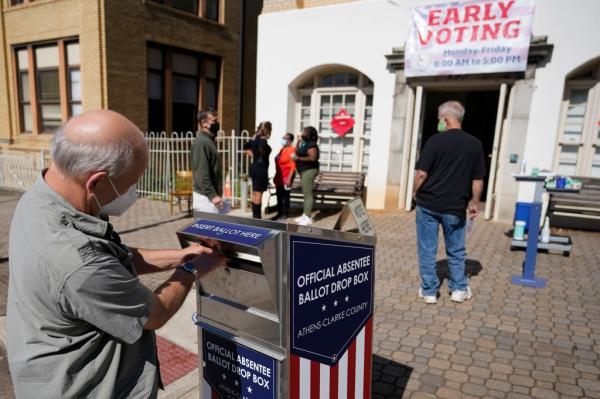 A man wearing a mask submitting a ballot in an official drop box during early voting in Athens, Georgia on October 19, 2020