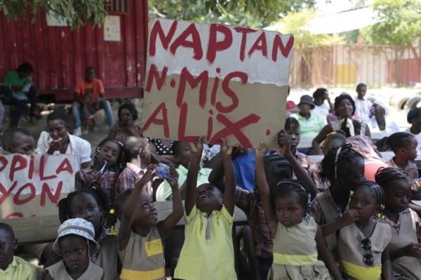 El Roi Academy students hold up a sign that reads in Creole 