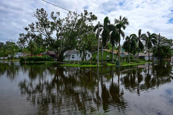 A flooded street in Tampa, Florida after the destruction caused by Hurricane Milton in 2024, with houses and trees partially submerged in water.