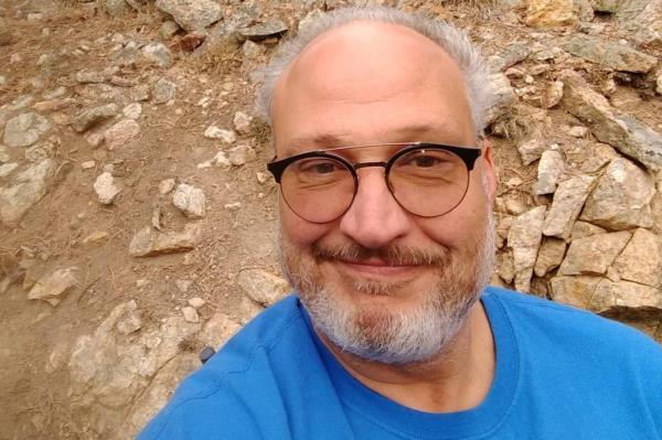 Close-up of a man with grey hair and glasses.