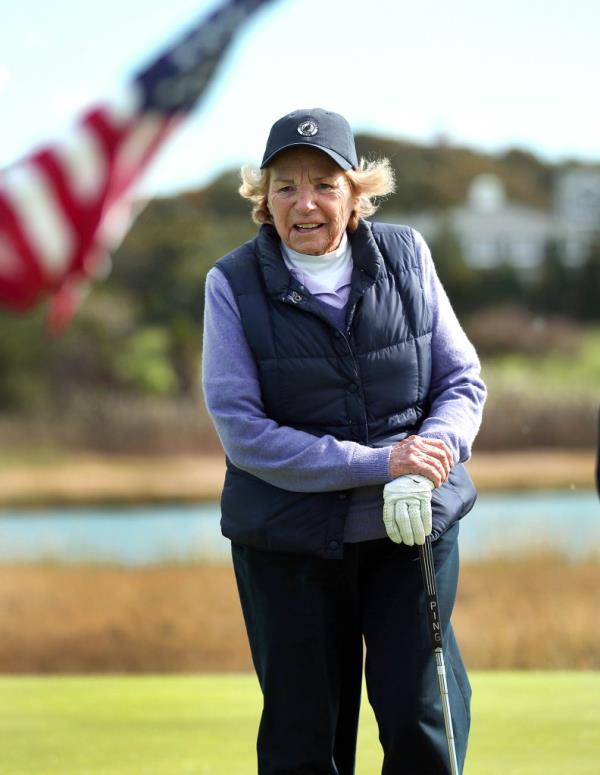 Ethel on a golf course, with an american flag flying behind her  