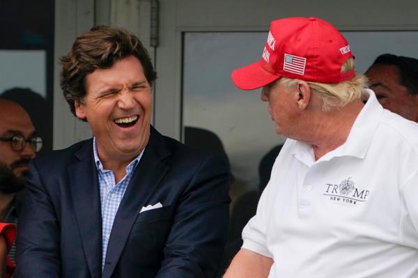 Tucker Carlson, left, and former President Do<em></em>nald Trump, right, react during the final round of the Bedminster Invitatio<em></em>nal LIV Golf tournament in Bedminster, N.J., July 31, 2022