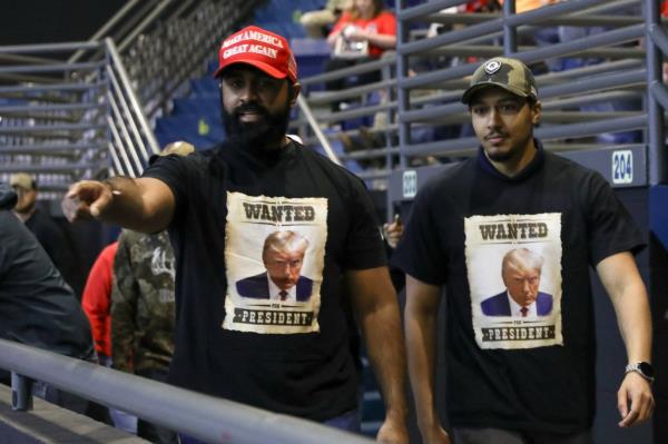 Two men wearing shirts depicting Do<em></em>nald Trump's mugshot as a Wanted poster