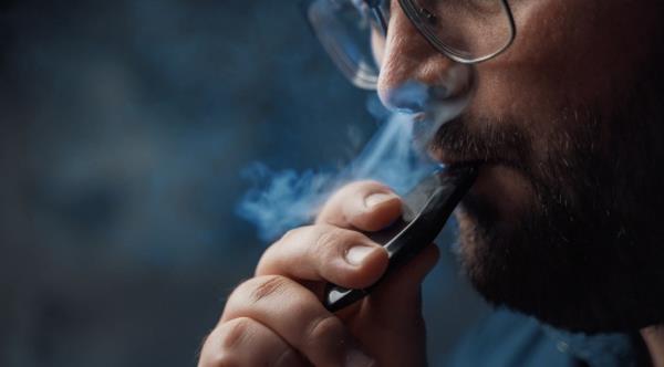 A man smokes from an electro<em></em>nic cigarette. 