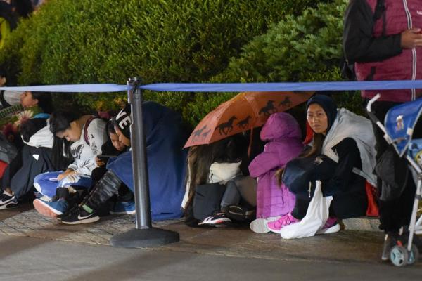 Migrants with young children wait in line in the early hours of Friday.