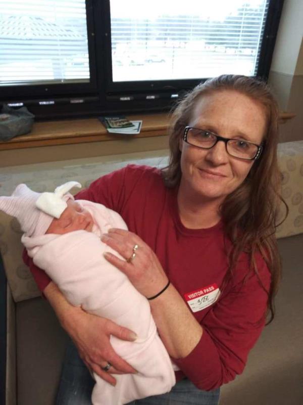 Amy Hogue posing with a newborn baby.