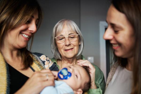 Grandmother looking at her newborn grandson in the arm of his mother