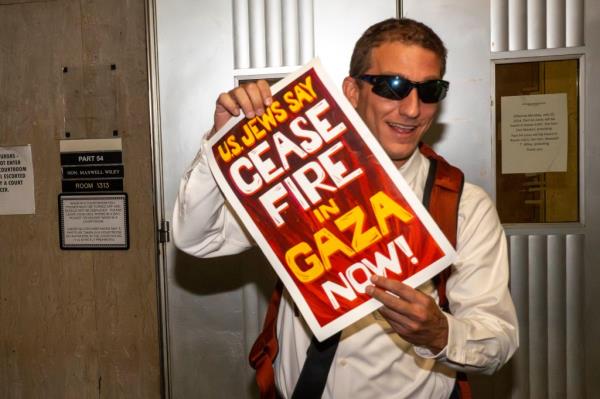 Carlson holding up a sign calling for a cease fire in Gaza.