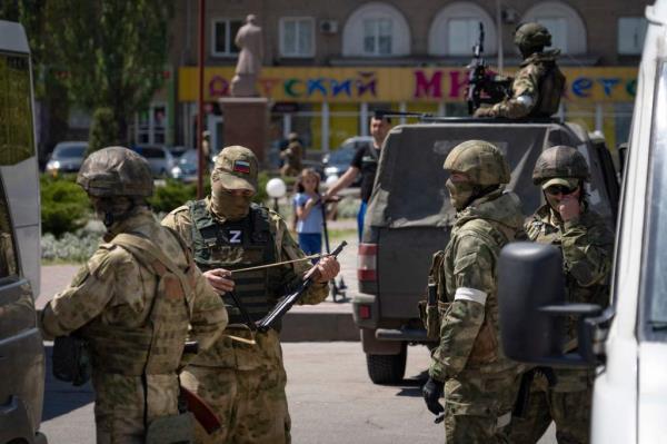 Russian servicemen patrol a street in Melitopol on May 1, 2022