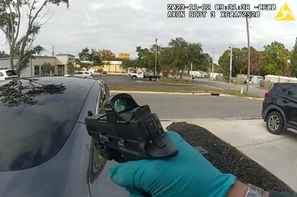 A hand holding a gun in body cam footage