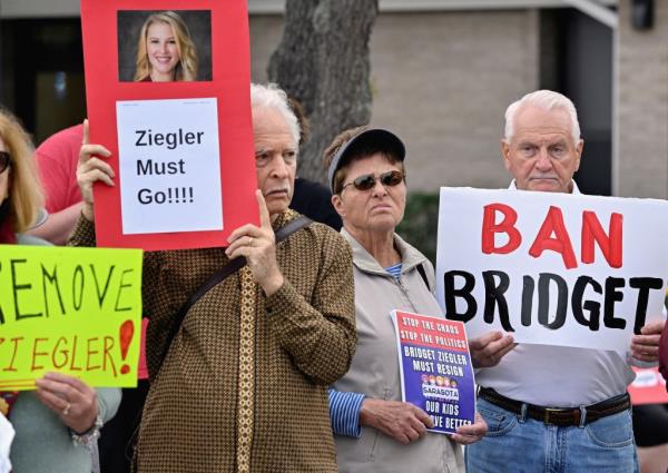 Protestors hold signs in favor of the public education support group Support Our Schools calling for the resignation of Sarasota County School Board member Bridget Ziegler