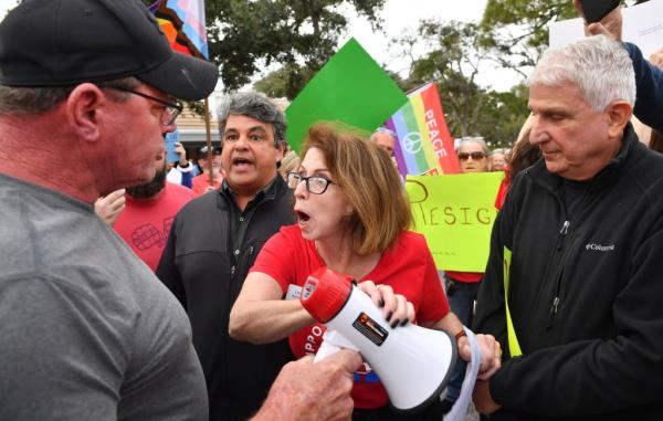 Lisa Schurr, center, with Support Our Schools, briefly stops John Wilson, right, from using his megaphone after Wilson tried to disrupt a protest outside the Sarasota County School Board, Tuesday