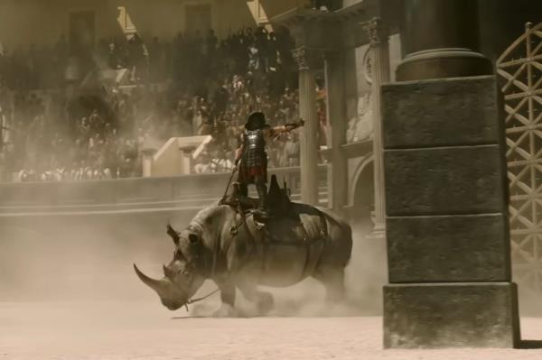 Man riding a rhinoceros in a scene from Gladiator II movie trailer