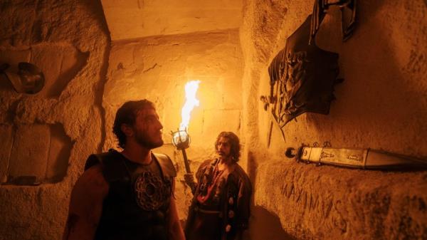 Actors Paul Mescal as Lucius and Alexander Karim as Ravi in a scene from Gladiator II, set in a cave