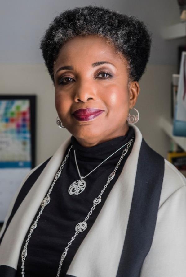 Dr Carol Swain  wears aa black and beige outfit, with silver earrings and necklaces, and smiles for a head shot.