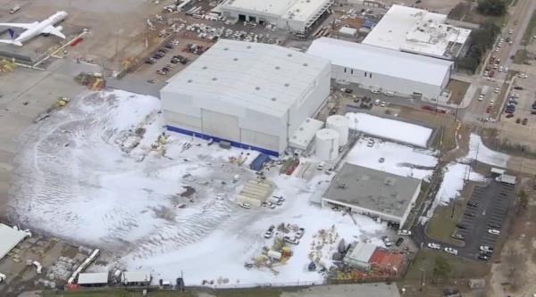 Aerial view of foam covering ground outside airport hangar 