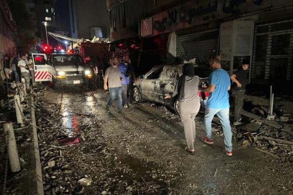 People walk near the building that was hit by an Israeli airstrike in the southern suburbs of Beirut, Lebanon.