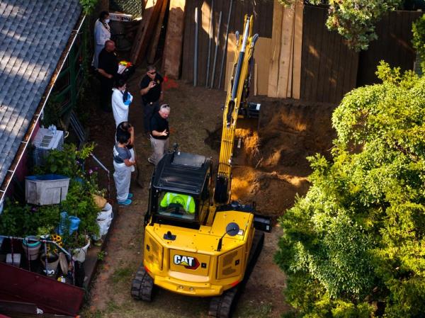 Crime scene investigators dig for evidence with a backhoe in Heuermann's backyard.