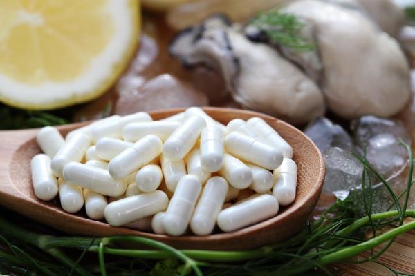 white zinc supplements with fresh oysters on a wood surface