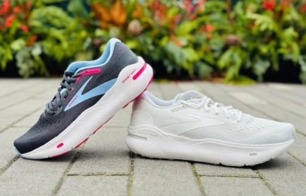 Two Brooks Ghost Max women's sneakers on a stone surface outside