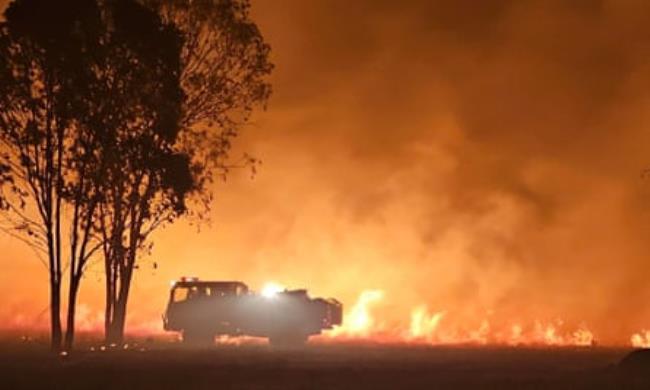 A fire truck sillhouetted against flames 