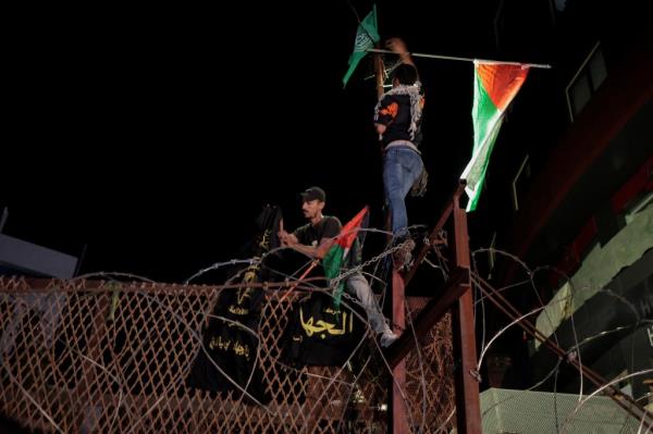 Lebanese protesters hang the Palestinian flag  and signs on fence of  the US embassy fence.