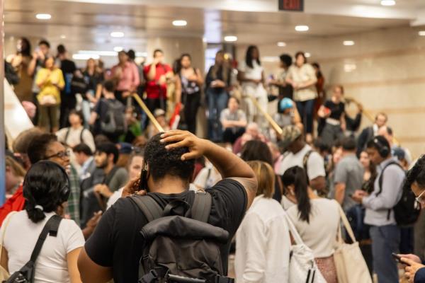 Stranded NJ Transit passengers at Penn Station due to train delays and cancellations, with a man talking on a cell phone in crowd