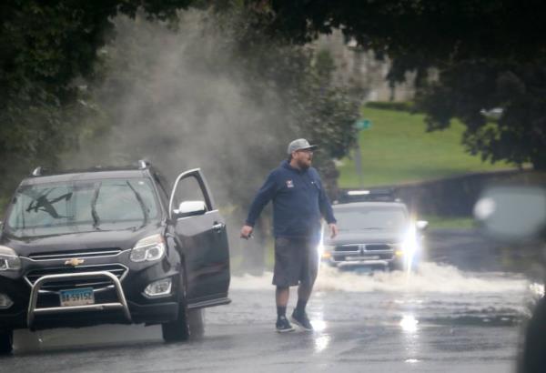 Man exiting his stalled car on a flooded Southern Blvd in Danbury, Connecticut, August 18, 2024, with other cars in the background