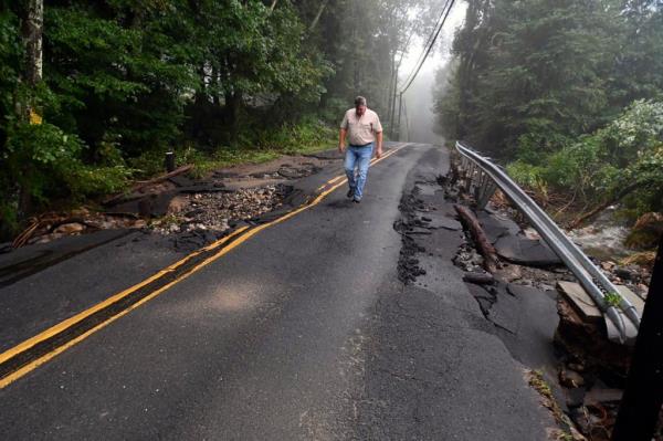 A Co<em></em>nnecticut Department of Energy and Enviro<em></em>nmental Protection employee inspecting the damage on a road in Southbury.