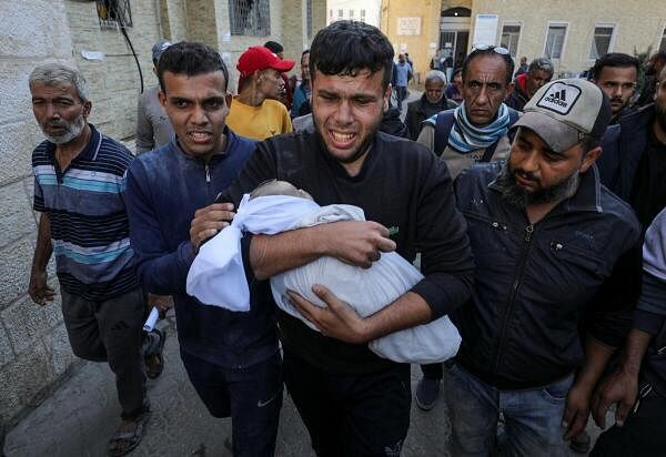 A man carries the body of Palestinian baby Ahmed Erheem, who medics said was killed in an Israeli strike, in Gaza City.