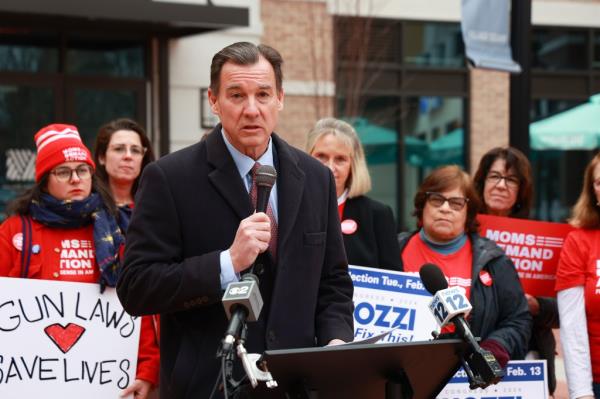 Thomas Suozzi speaking at a podium surrounded by micropho<em></em>nes and people for his campaign trail in Glen Cove, NY