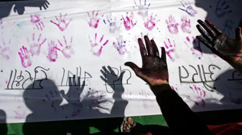 Getty Images A file photo of An Indian woman looking at her hands after making a hand impression on a banner during a street march against sexual harassment and marital violence to mark Internatio<em></em>nal Women's Day in New Delhi